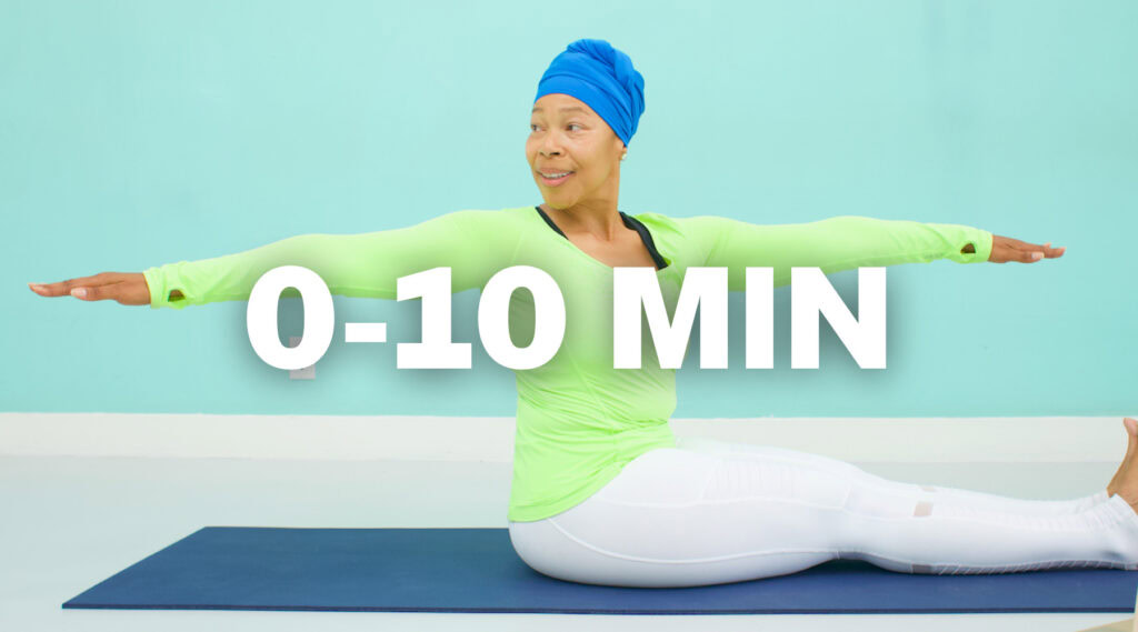 Woman in green workout outfit performing seated stretch for flexibility.